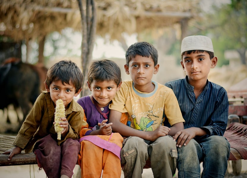 Four Children Sitting on Brown Charpai Bed